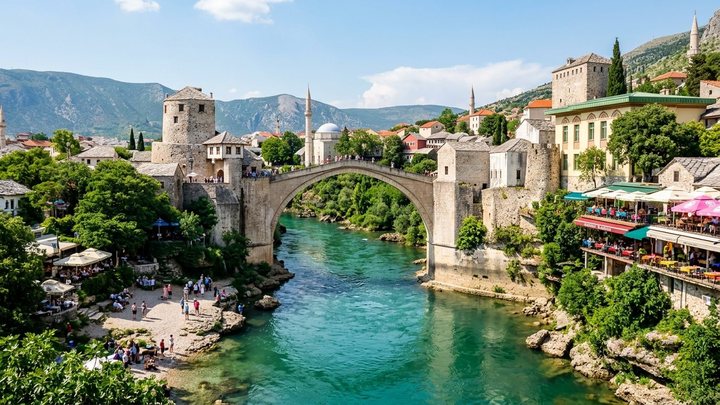Pogled na Stari most u Mostaru iznad tirkizne Neretve sa kamenim kulama Tara i Halebija